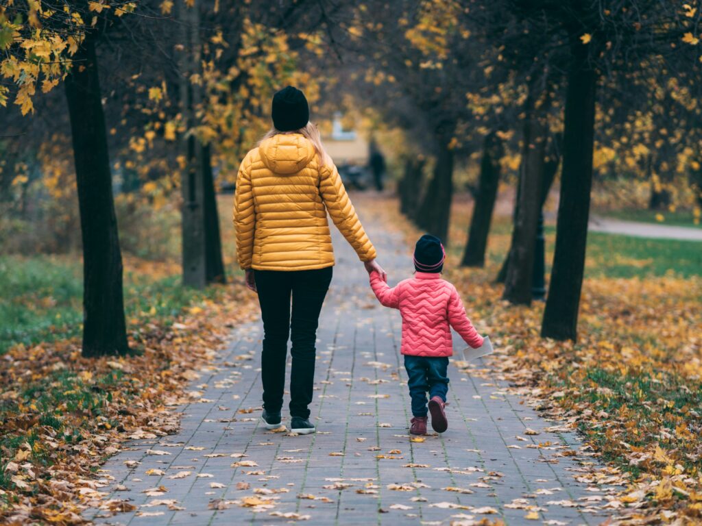 Mother and daughter walking in the fall leaves.